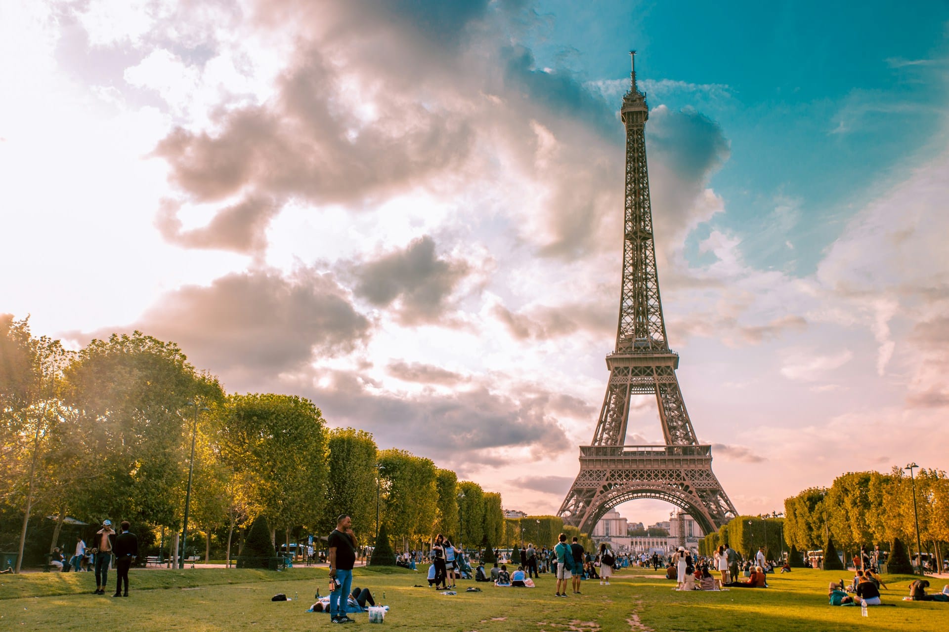 A panoramic view of the Eiffel Tower surrounded by lush greenery and tourists enjoying the scenery