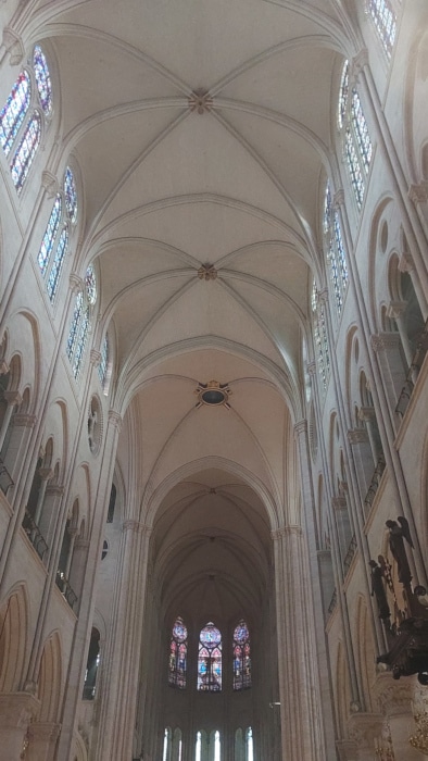 Notre Dame Cathedral Paris interior nave after restoration showing brilliant white cleaned limestone columns and vaulted ceiling with visitors.