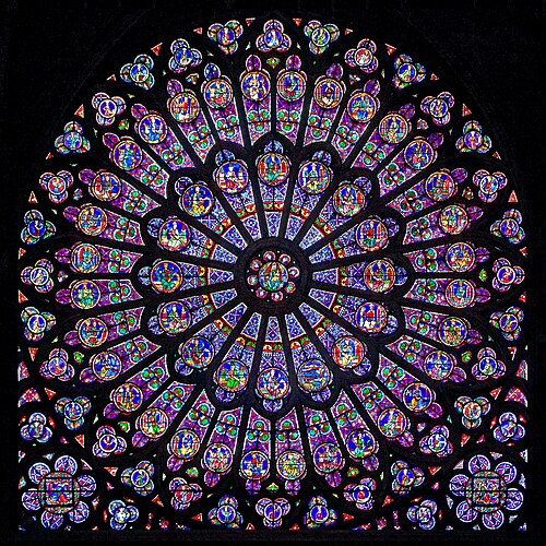 The north rose window of Notre Dame Cathedral showing the Virgin Mary surrounded by Old Testament figures in brilliant blues.