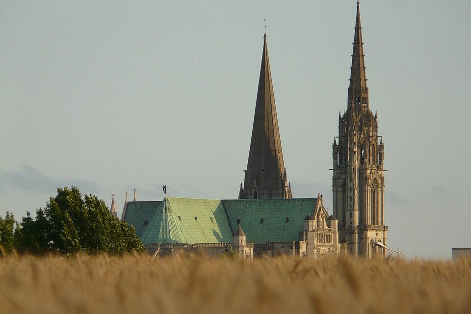 Chartres Cathedral rising above the Beauce plain, asymmetric north and south towers silhouetted against the sky, visible for 25 kilometers across the flat wheat fields of Eure-et-Loir